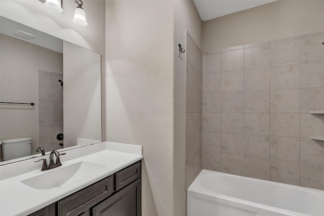 full bathroom with vanity, tiled shower / bath combo, and toilet