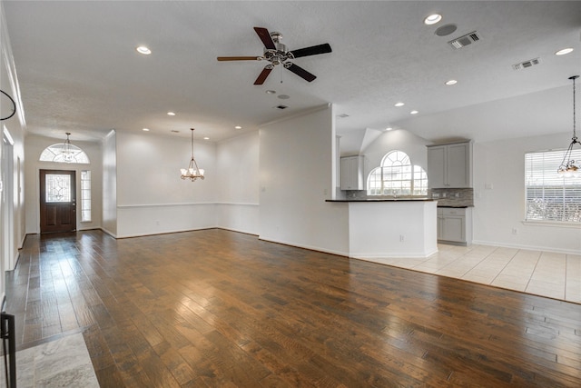 unfurnished living room featuring lofted ceiling, a healthy amount of sunlight, and light hardwood / wood-style flooring