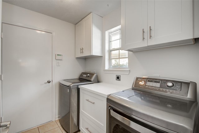 laundry area featuring cabinets, light tile patterned floors, and washer and clothes dryer