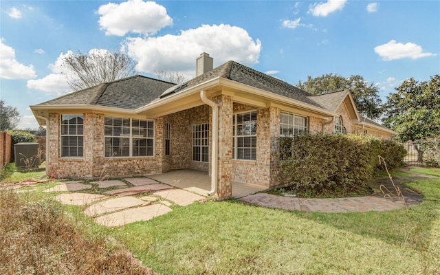 rear view of house featuring a lawn and a patio