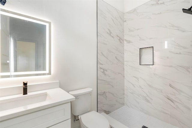 bathroom with vanity, tiled shower, and toilet