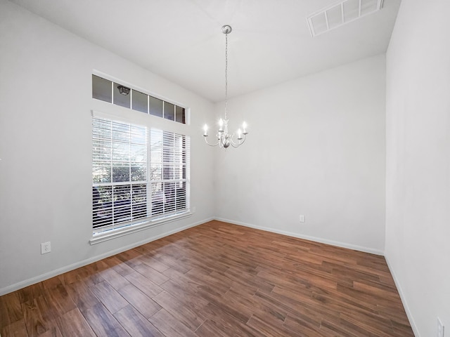 spare room with dark hardwood / wood-style floors and a chandelier