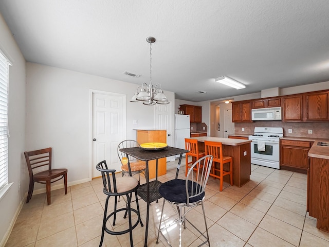 kitchen with decorative backsplash, hanging light fixtures, a center island, light tile patterned floors, and white appliances