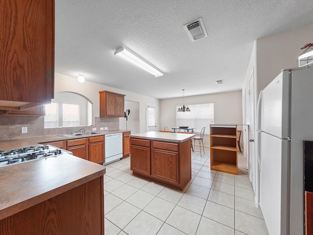 kitchen with white appliances, sink, a kitchen island, and light tile patterned floors