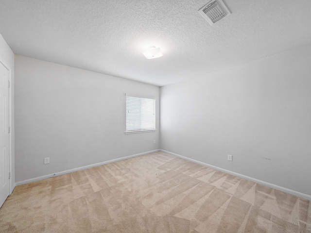 empty room with light colored carpet and a textured ceiling