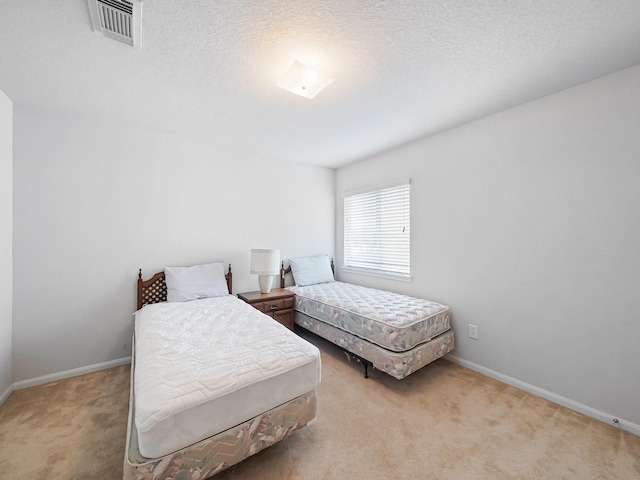 bedroom featuring light carpet and a textured ceiling