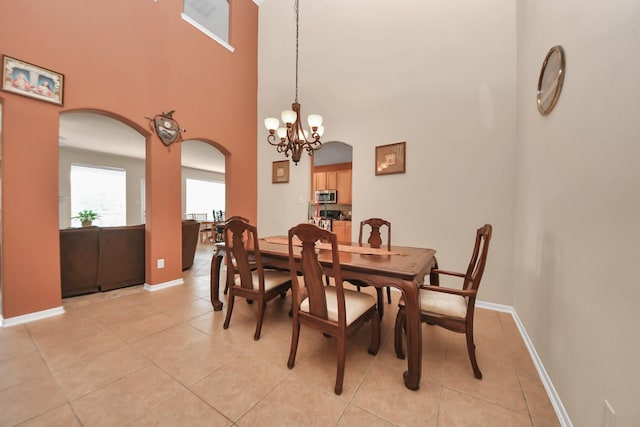 tiled dining space with a chandelier and a high ceiling