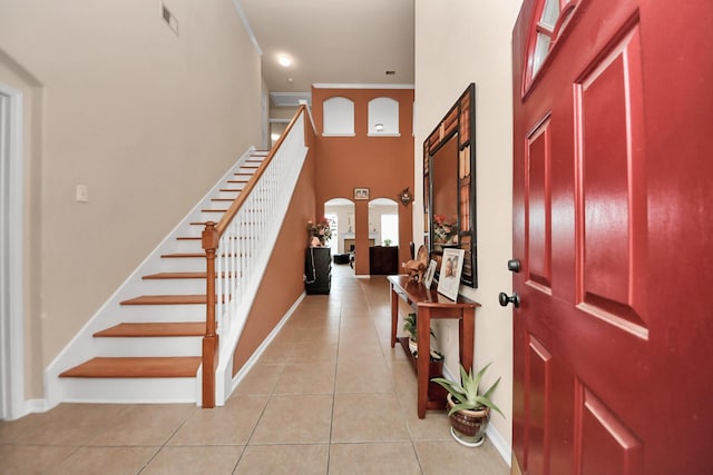 entrance foyer featuring a high ceiling, ornamental molding, and light tile patterned floors