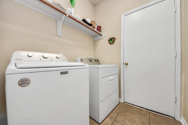 clothes washing area featuring washer and clothes dryer and light tile patterned floors