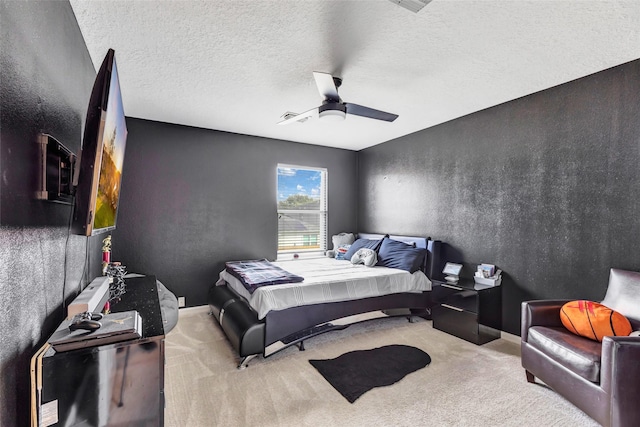 bedroom with ceiling fan, light colored carpet, and a textured ceiling