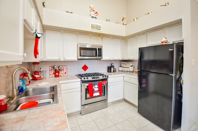 kitchen featuring sink, white cabinetry, light tile patterned floors, stainless steel appliances, and decorative backsplash