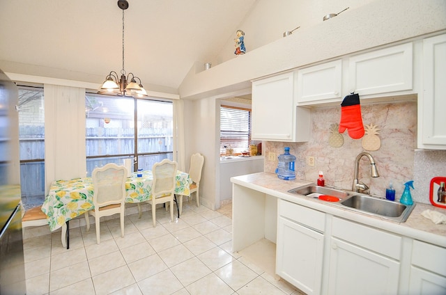 kitchen with pendant lighting, white cabinetry, vaulted ceiling, and sink