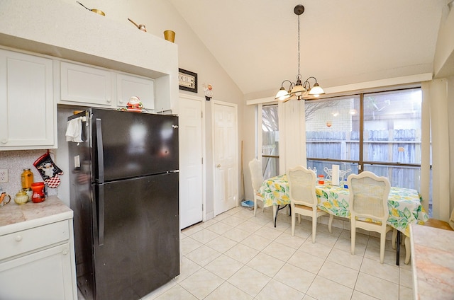 kitchen featuring black refrigerator, white cabinetry, a notable chandelier, decorative light fixtures, and vaulted ceiling