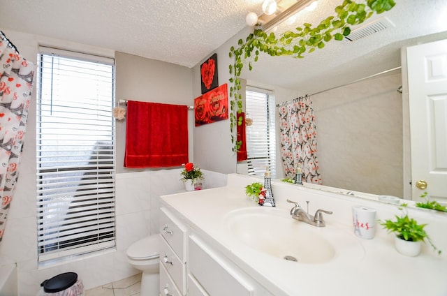 bathroom featuring vanity, a healthy amount of sunlight, toilet, and a textured ceiling