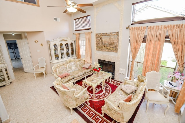 living room with a towering ceiling, plenty of natural light, and ceiling fan