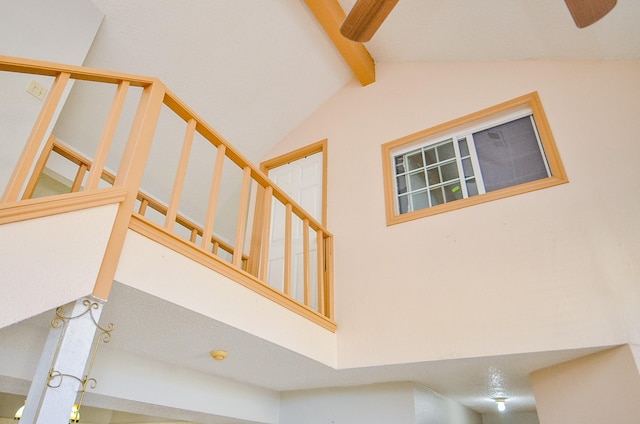 stairway with beamed ceiling and high vaulted ceiling