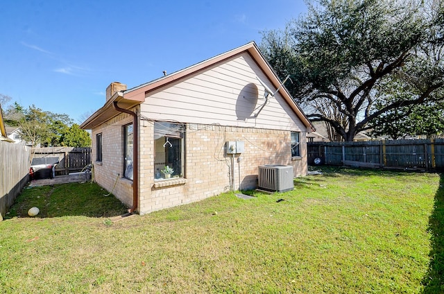 rear view of house featuring cooling unit and a yard