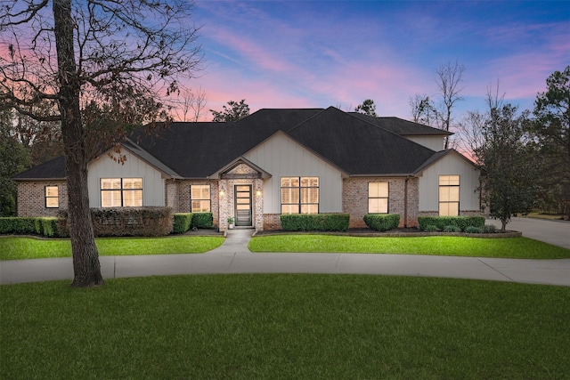 modern farmhouse featuring driveway, brick siding, and a front yard