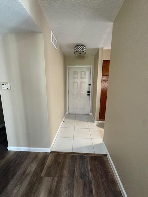 hall with a textured ceiling and light wood-type flooring