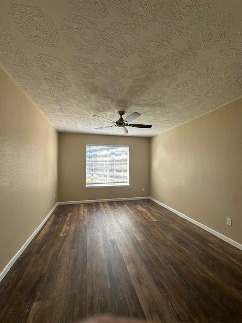 empty room with ceiling fan, a textured ceiling, and dark hardwood / wood-style flooring