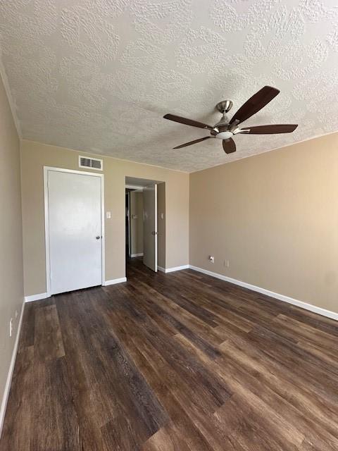 unfurnished bedroom with a textured ceiling, dark wood-type flooring, and ceiling fan