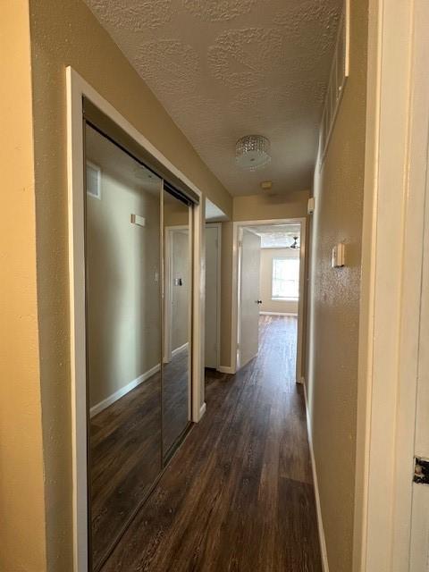 hall with dark hardwood / wood-style floors and a textured ceiling