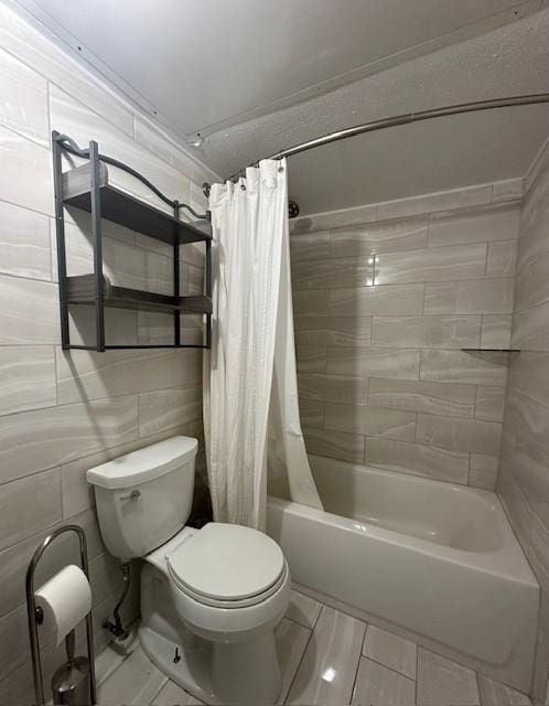 bathroom with tile walls, shower / tub combo with curtain, and toilet