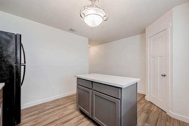 kitchen with gray cabinetry, a kitchen island, and black fridge