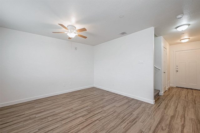 empty room with ceiling fan, a textured ceiling, and light wood-type flooring