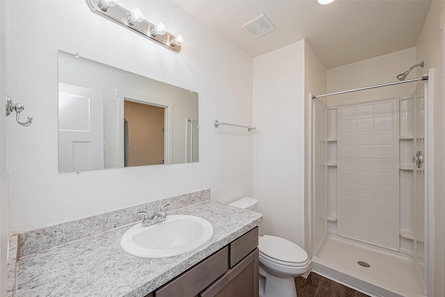 bathroom with hardwood / wood-style flooring, vanity, toilet, and a shower