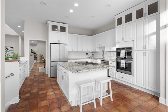 kitchen featuring a kitchen island, stainless steel appliances, white cabinets, a kitchen bar, and decorative backsplash