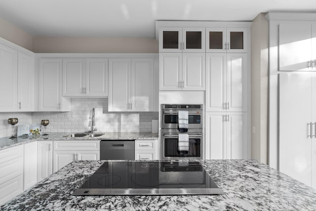 kitchen with sink, stainless steel appliances, light stone countertops, white cabinets, and decorative backsplash