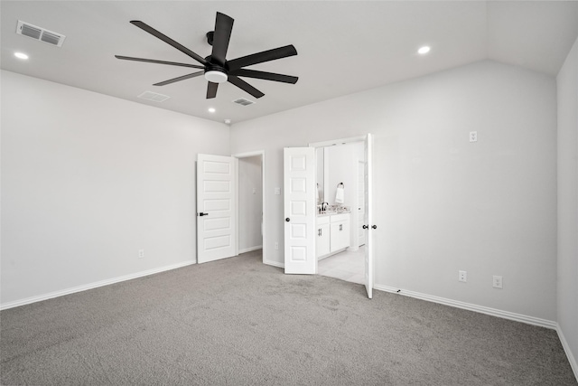 unfurnished bedroom featuring lofted ceiling, sink, light colored carpet, ceiling fan, and ensuite bath