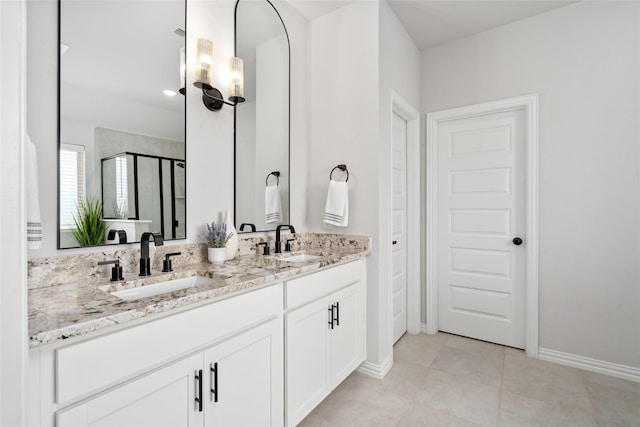 bathroom with a shower with door, vanity, and tile patterned flooring