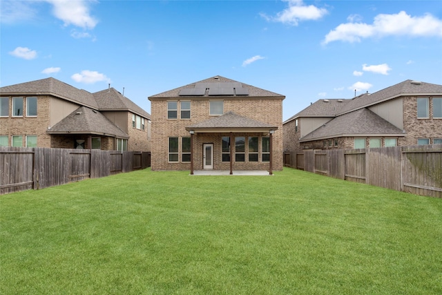 rear view of house with a yard, a patio area, and solar panels