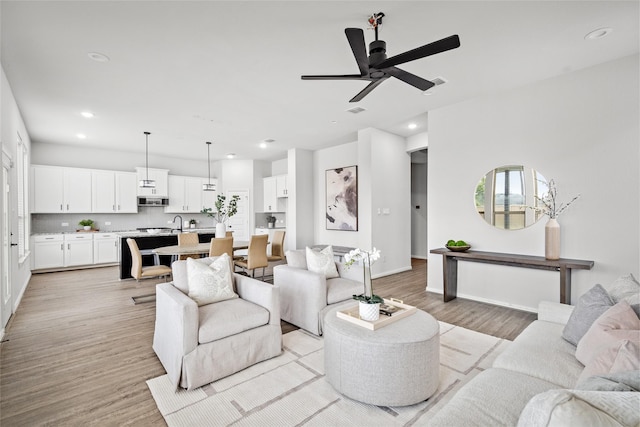 living room featuring ceiling fan, sink, and light hardwood / wood-style floors