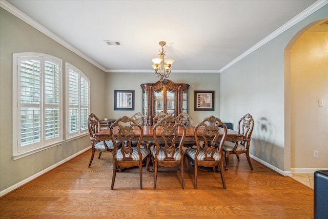 dining area with light wood-type flooring, a chandelier, and crown molding