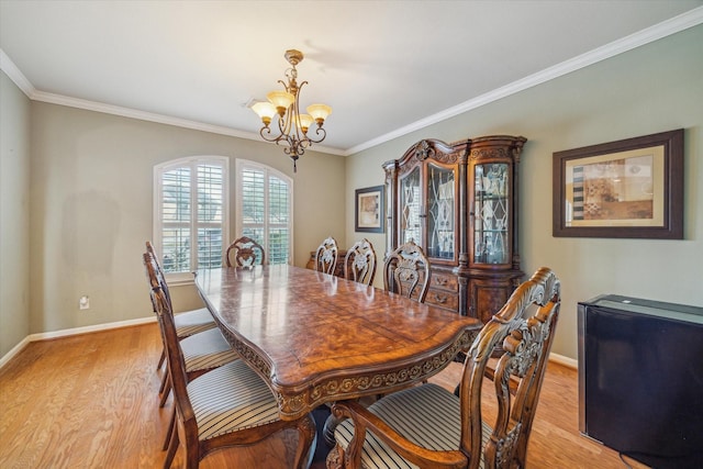 dining space featuring light wood-type flooring, an inviting chandelier, and crown molding