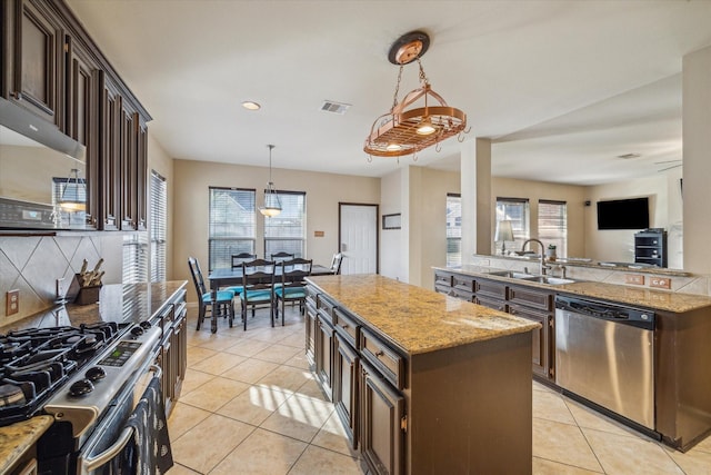 kitchen featuring sink, pendant lighting, a kitchen island, stainless steel appliances, and dark brown cabinets