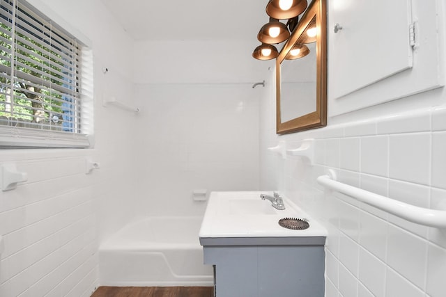 2713 John St, La Marque, TX 77568 - bathroom with shower / washtub combination, tile walls, wood finished floors, and vanity