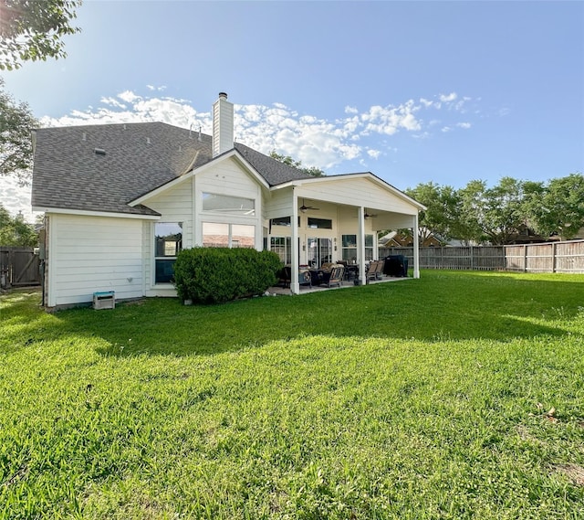 rear view of house featuring ceiling fan, a yard, and a patio