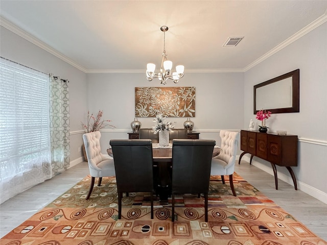 dining room with an inviting chandelier, crown molding, and light wood-type flooring