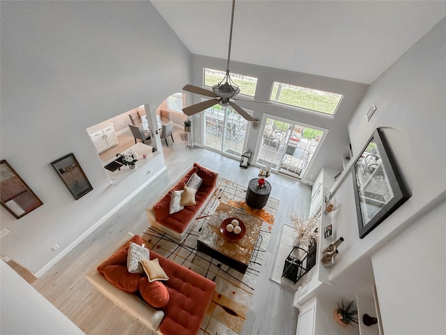 living room with a towering ceiling, ceiling fan, and hardwood / wood-style flooring