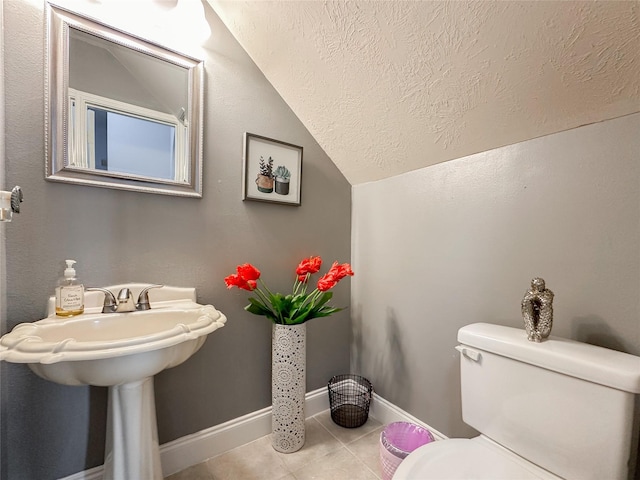 bathroom with lofted ceiling, toilet, and tile patterned flooring