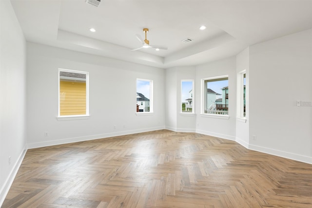 empty room featuring ceiling fan and a raised ceiling