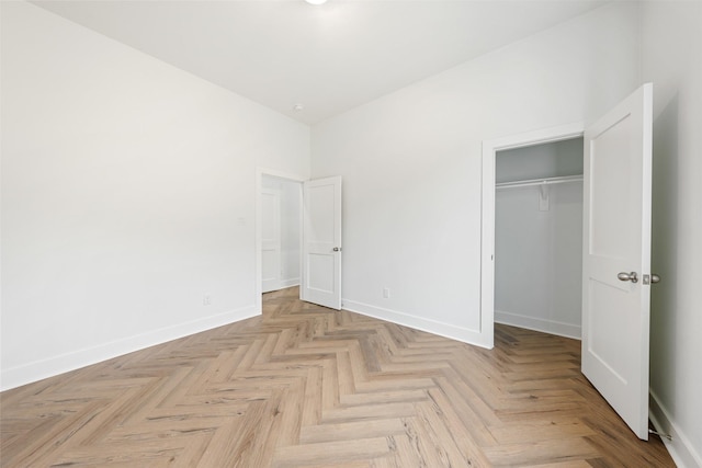 unfurnished bedroom featuring light parquet flooring and a closet