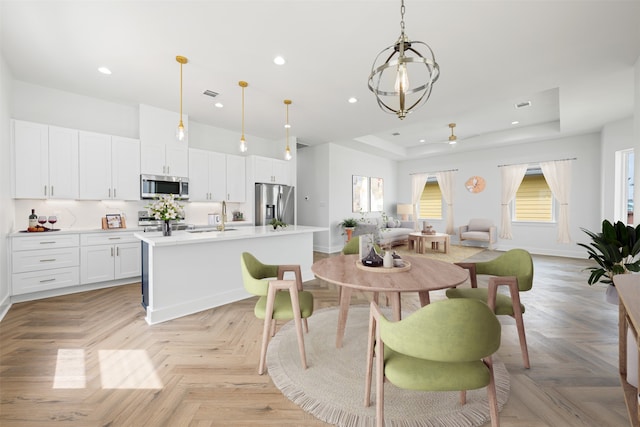 dining space featuring light parquet floors, sink, and a tray ceiling