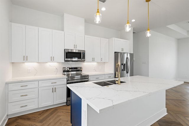 kitchen featuring pendant lighting, an island with sink, white cabinets, and appliances with stainless steel finishes