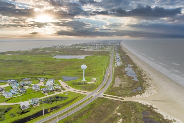 aerial view at dusk with a water view and a beach view