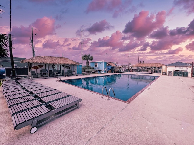 pool at dusk featuring a patio area